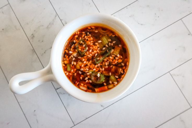 a white bowl filled with lots of food on top of a marble counter next to a tile floor