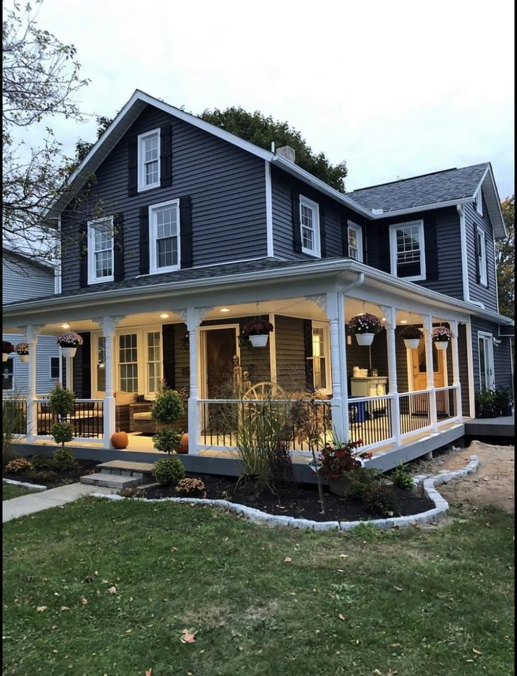 a house that is lit up with lights on the front porch and covered in plants