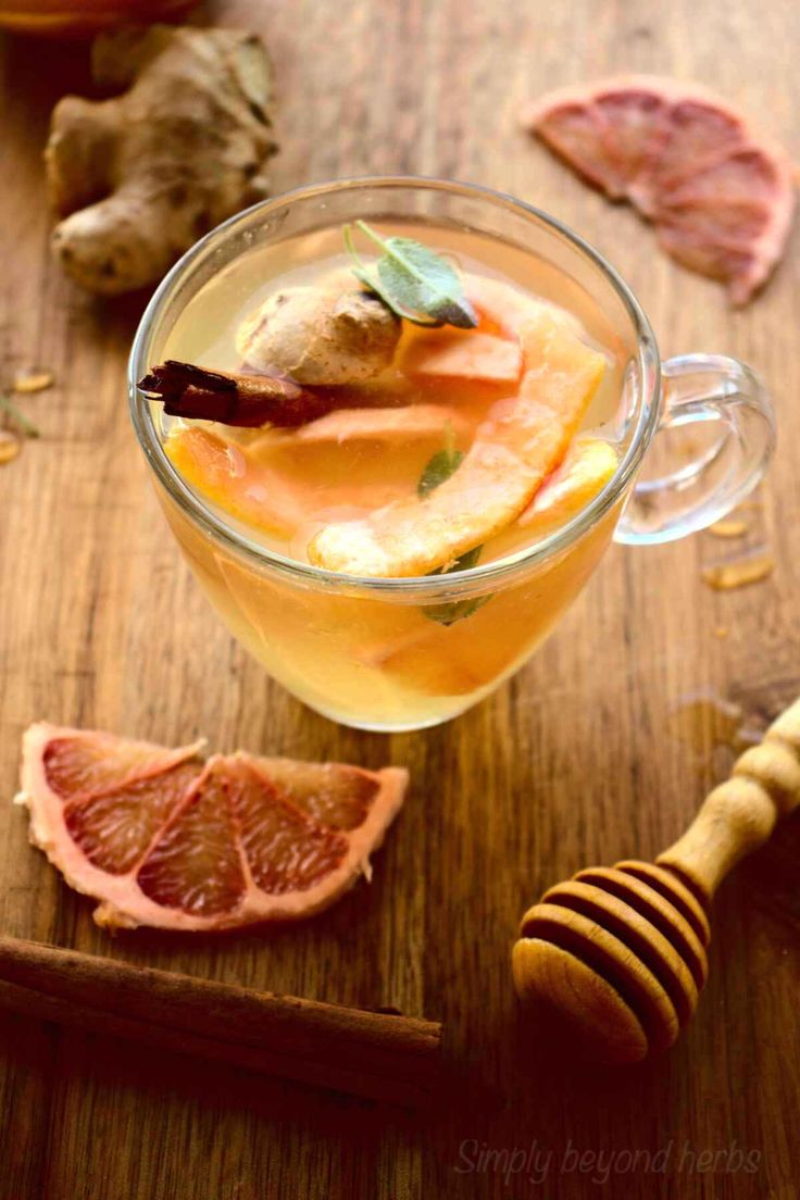 a glass cup filled with liquid next to sliced oranges