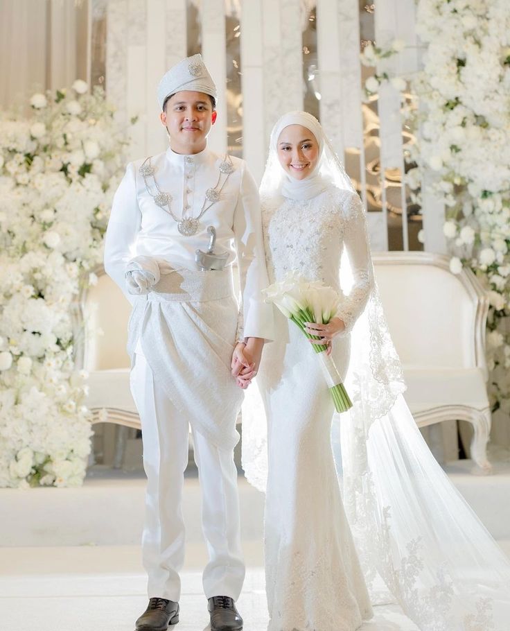 two people dressed in white standing next to each other