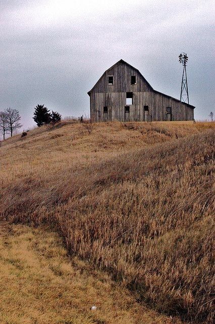 an old barn sits on top of a hill