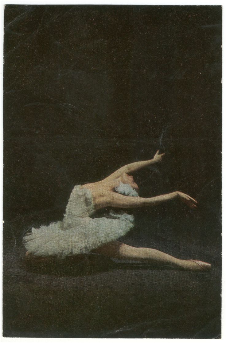 a ballerina in white tutu and feathered skirt is holding her leg up