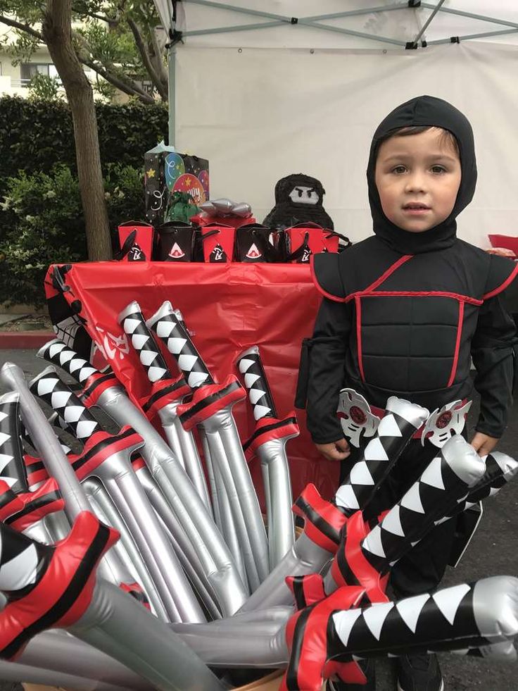 a young boy dressed in costume standing next to an assortment of halloween decorations