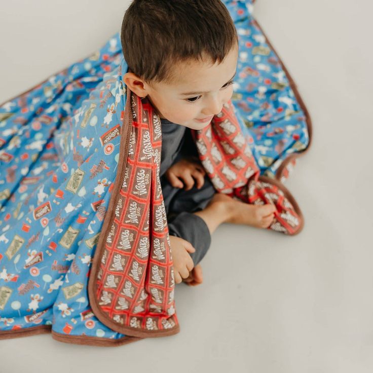 a little boy sitting on the floor with a blanket