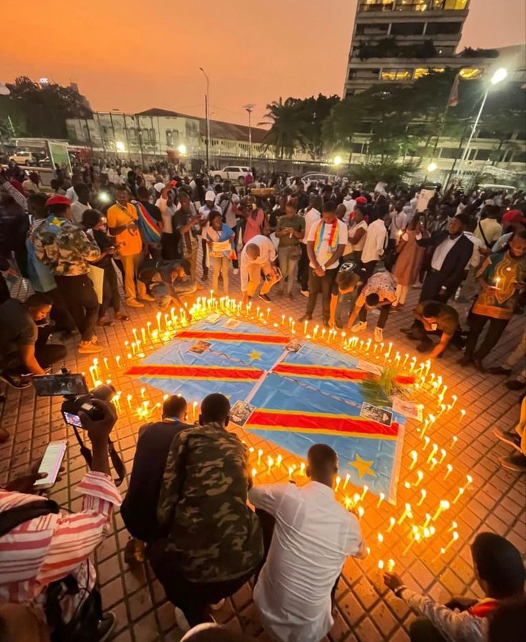 many people are gathered around candles on the ground