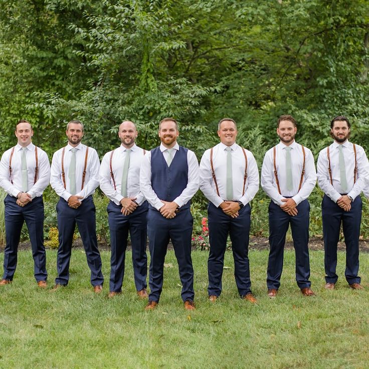 a group of men standing next to each other on top of a lush green field