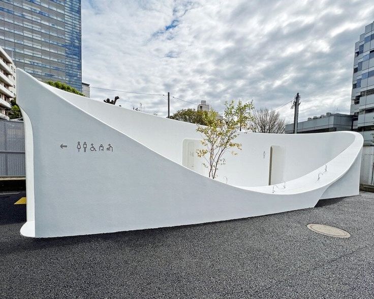 a large white sculpture in the middle of a parking lot next to tall buildings and trees