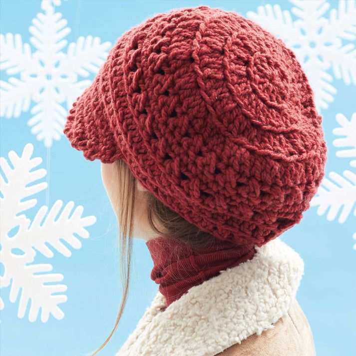 a woman wearing a red knitted hat and scarf in front of snowflakes