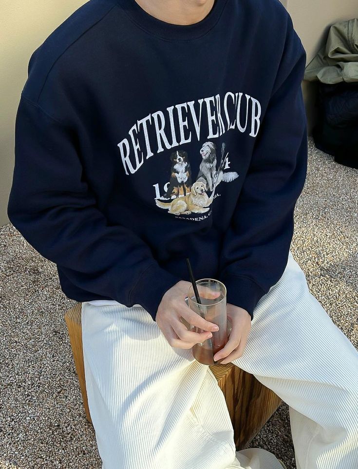 a young man sitting on top of a wooden chair holding a drink in his hand