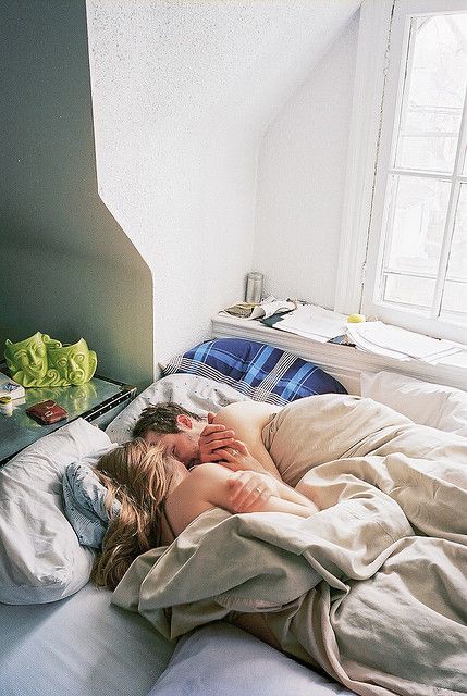 a woman laying in bed with her head on the pillow and another person sleeping next to her