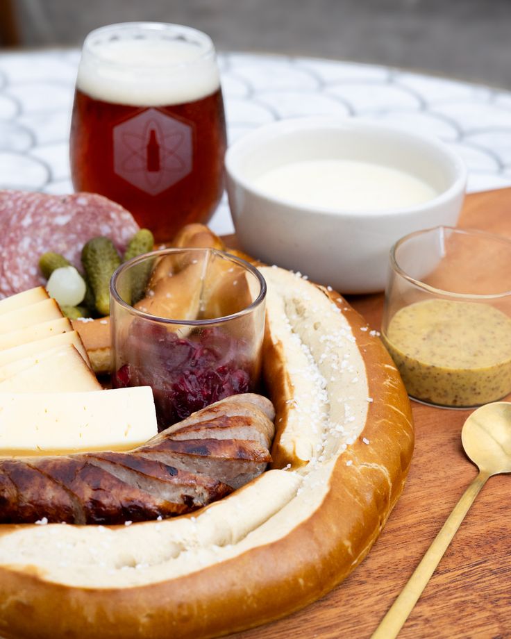 a wooden tray topped with lots of different types of food next to glasses and spoons