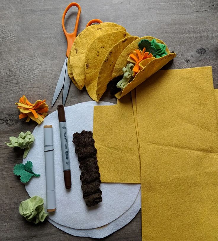 a table topped with tacos and scissors next to yellow napkins on top of a white plate