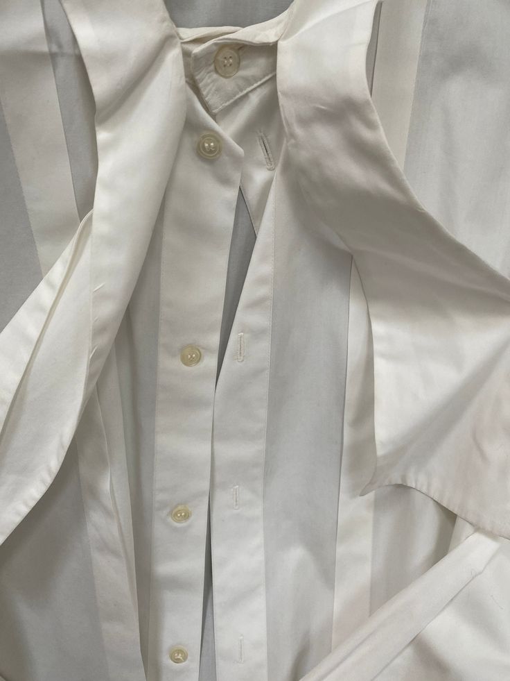 I would say it is 1970s to 80s.  Lovely I. Magnin ( The best clothing store in San Francisco for about 100 years or so)  white shirt is sharp for the well dressed gentleman.  Cotton pure. Perfect condition. * All of our items are unique/one-of-a-kind and are sold as is. * All measurements and descriptions are approximate White Business Tops For Summer, White Dress Shirt For Office In Spring, White Dress Shirt For Spring Office Wear, White Formal Dress Shirt For Spring, White Button-up Dress Shirt For Daywear, White Shirt With Spread Collar For Daywear, White Spread Collar Shirt For Daywear, Classic White Tops For Daywear, White Formal Button-up Tops