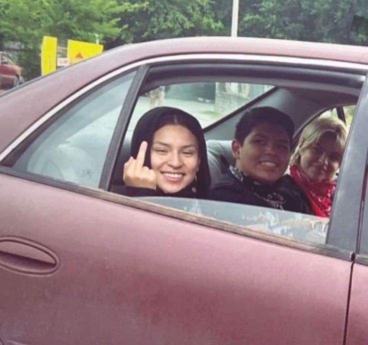 two people sitting in a car giving the peace sign