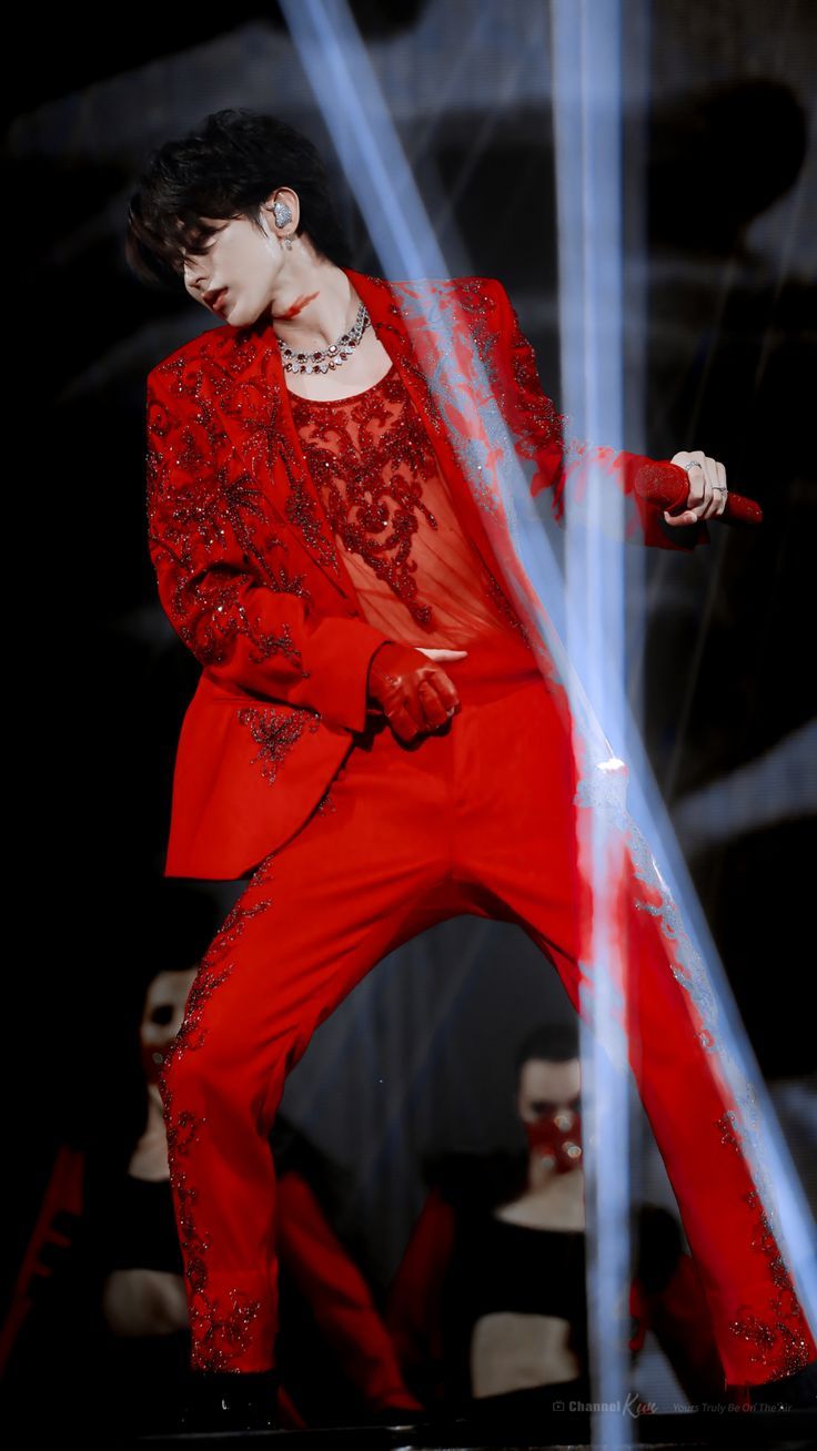 a male in a red suit is performing on stage