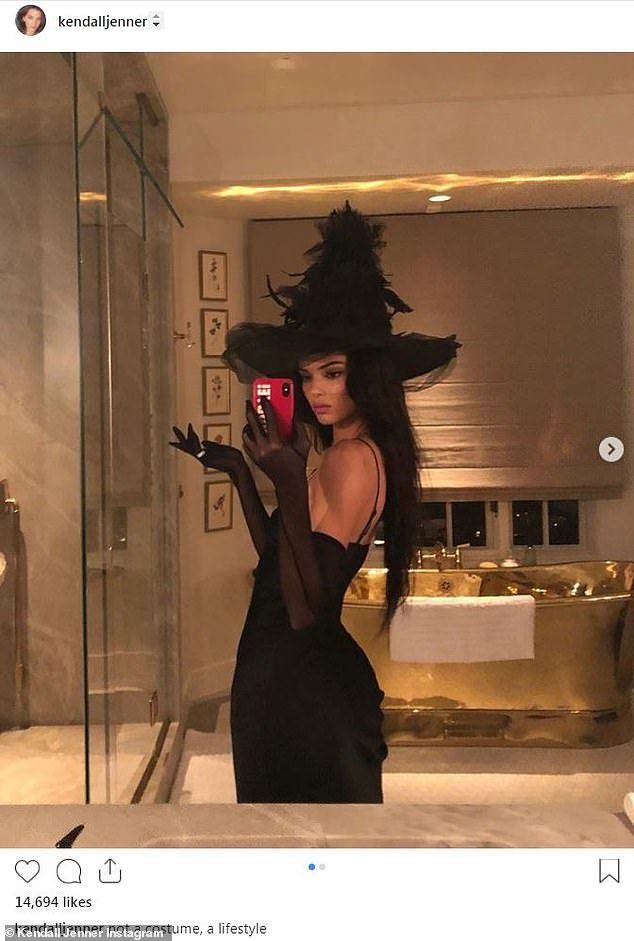 a woman is taking a selfie in the bathroom with her cell phone while wearing a black dress and hat