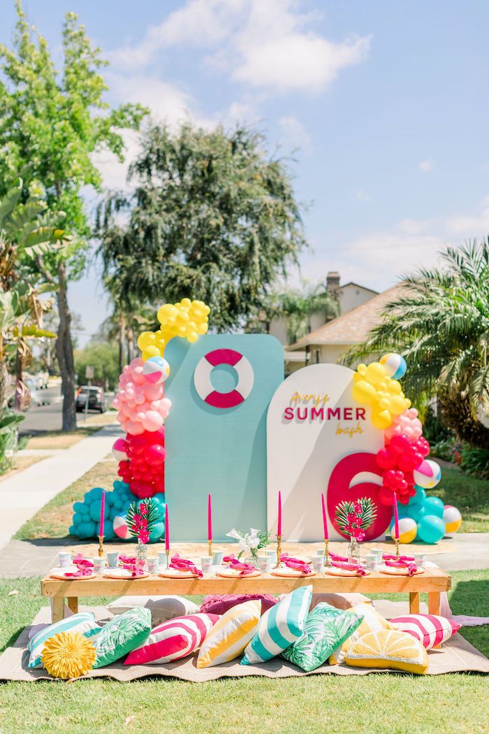 the table is set up for an outdoor party with balloons and decorations on top of it