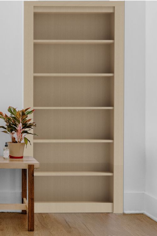 a plant is sitting on a small table in front of a bookcase with shelves