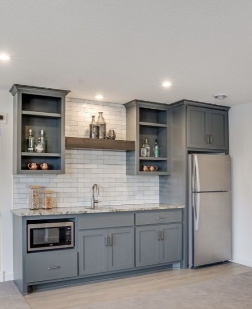 a kitchen with gray cabinets and white tile backsplash