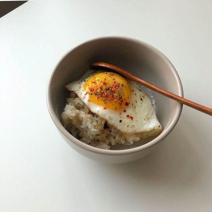 an egg and rice dish in a bowl with chopsticks next to it on a table