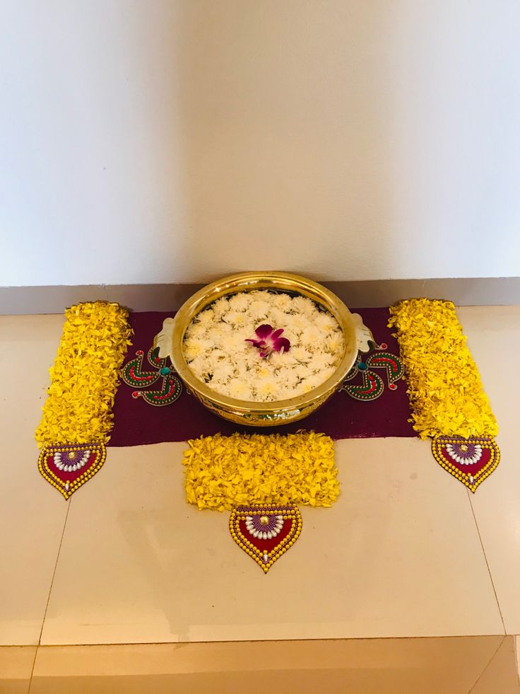 a bowl filled with rice sitting on top of a table covered in yellow and red flowers