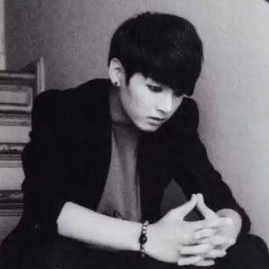 a young man sitting on top of a bed next to a stack of books wearing a watch