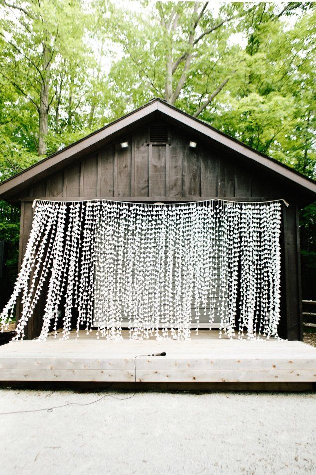 a wooden structure with white beads hanging from it's sides in front of trees