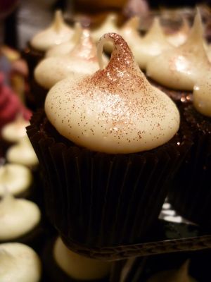 cupcakes with white frosting and brown sprinkles sitting on top of each other