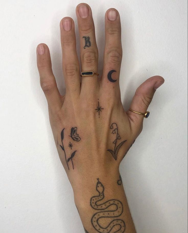 a person's hand with tattoos on it and a name tag in the middle