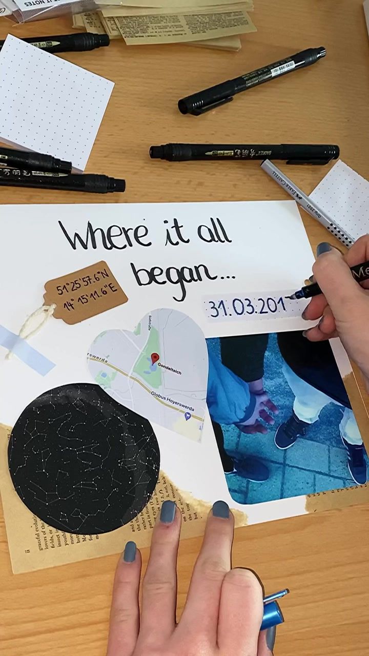 a person is cutting out a piece of paper on top of a table with markers and pens