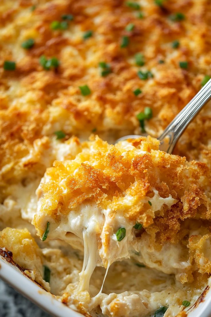 a close up of a spoon in a casserole dish with chicken and cheese