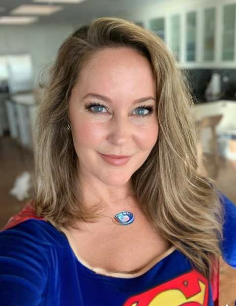 a woman wearing a superman shirt is smiling for the camera