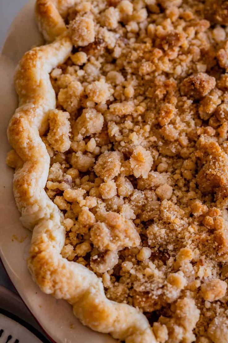 a pie with crumbs on it sitting on top of a white platter