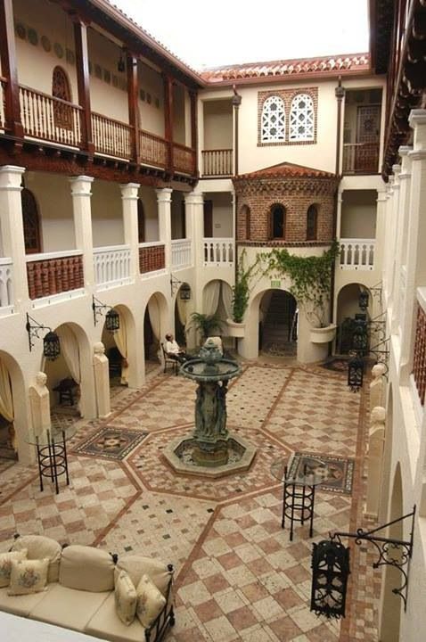 an indoor courtyard with fountain, seating and potted plant in the center on tiled flooring