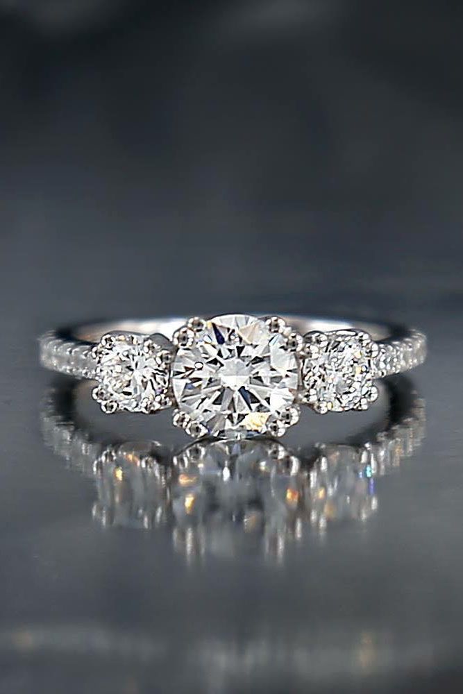 a three stone diamond ring on a reflective surface