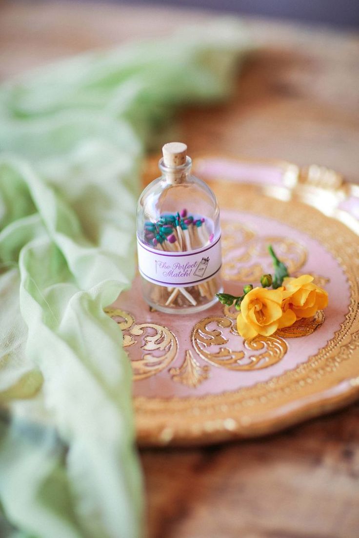 a bottle of perfume sitting on top of a pink plate with yellow flowers in it