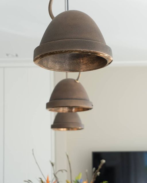 an old fashioned light hanging from a ceiling in a living room with flowers on the table