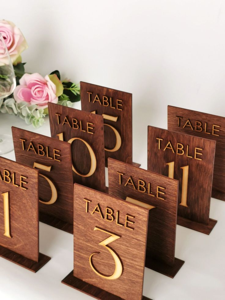 wooden table numbers with flowers in the background