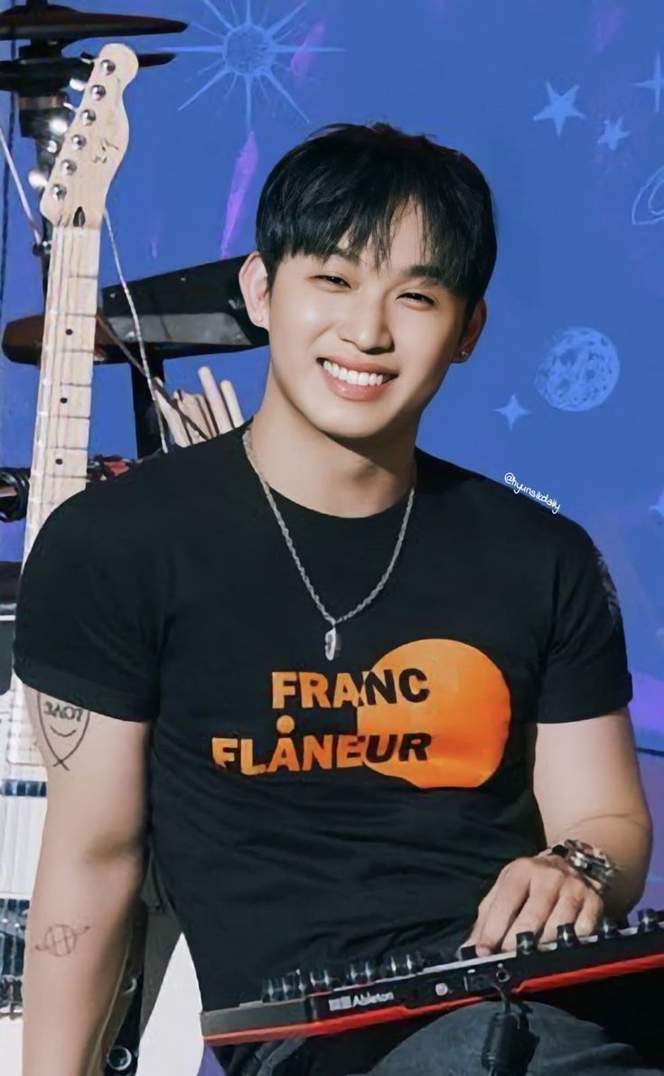 a young man sitting in front of a guitar