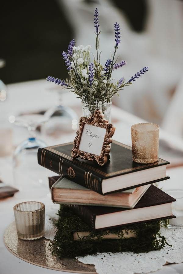 a stack of books sitting on top of a table next to a vase filled with flowers