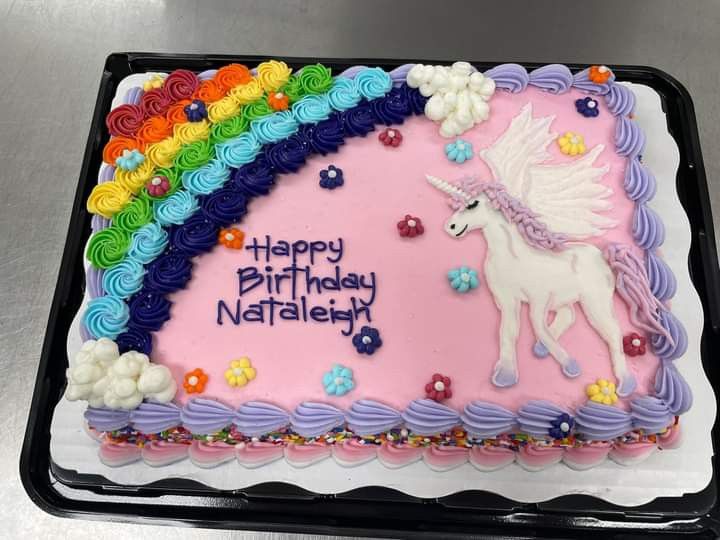 a birthday cake decorated with an unicorn and rainbows on it's side is shown