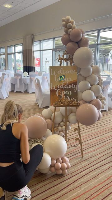 a woman sitting on the floor with balloons in front of her and a sign that says welcome to our wedding day