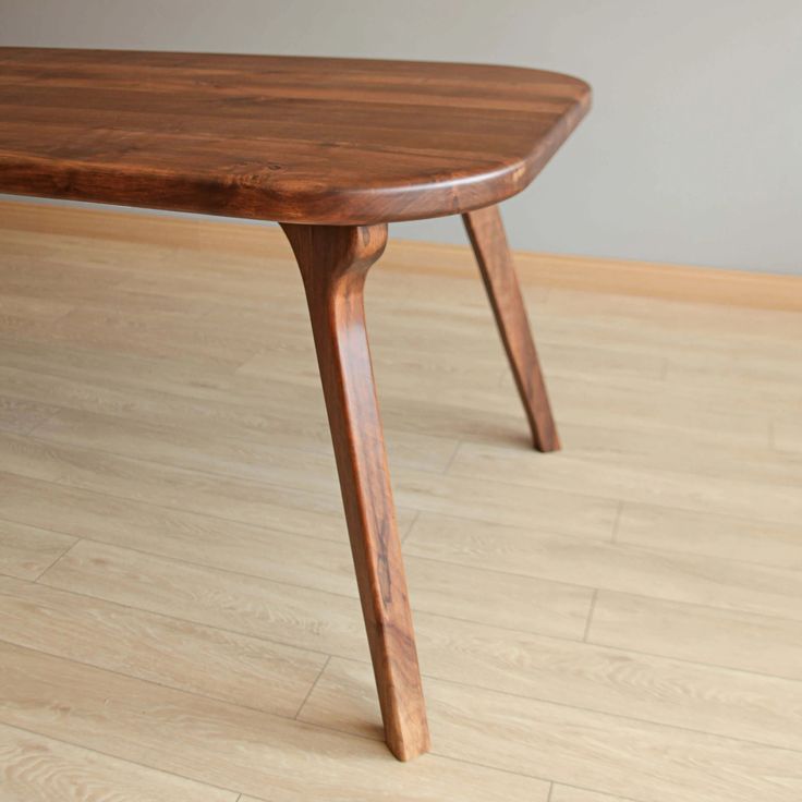 a wooden table sitting on top of a hard wood floor next to a white wall