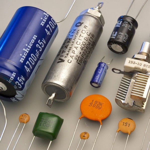 many different types of electronic components on a white surface with blue and orange capacitors