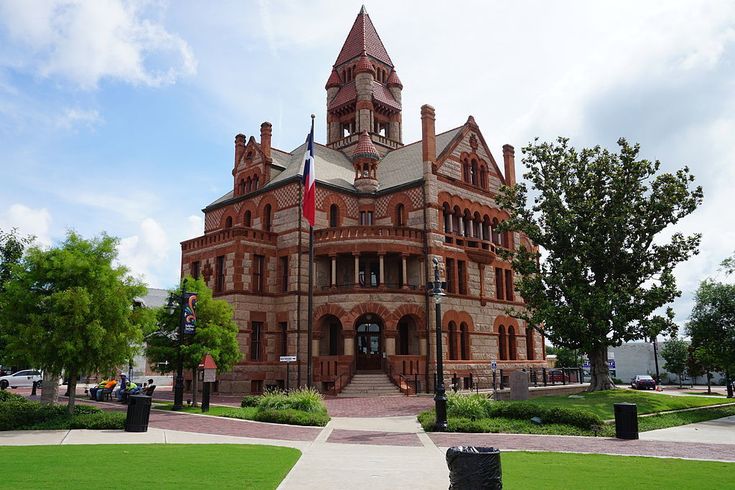 an old brick building with a clock tower on top and flags flying in the wind