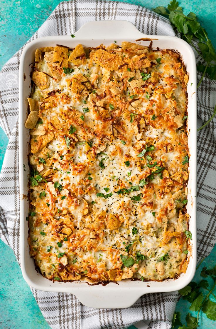 a casserole dish with cheese and parsley in it on a checkered cloth