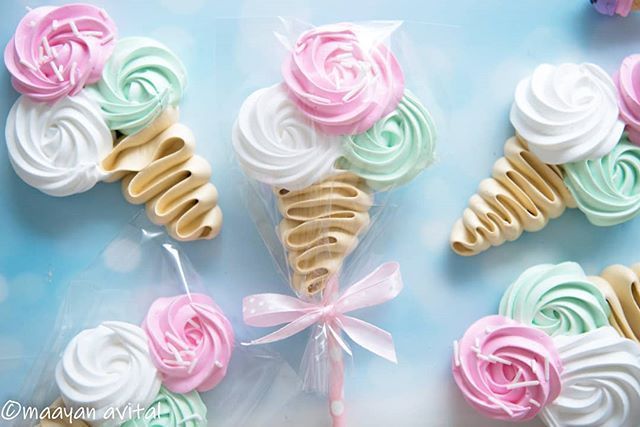 cupcakes decorated with icing and flowers on a blue tablecloth next to candy lollipops