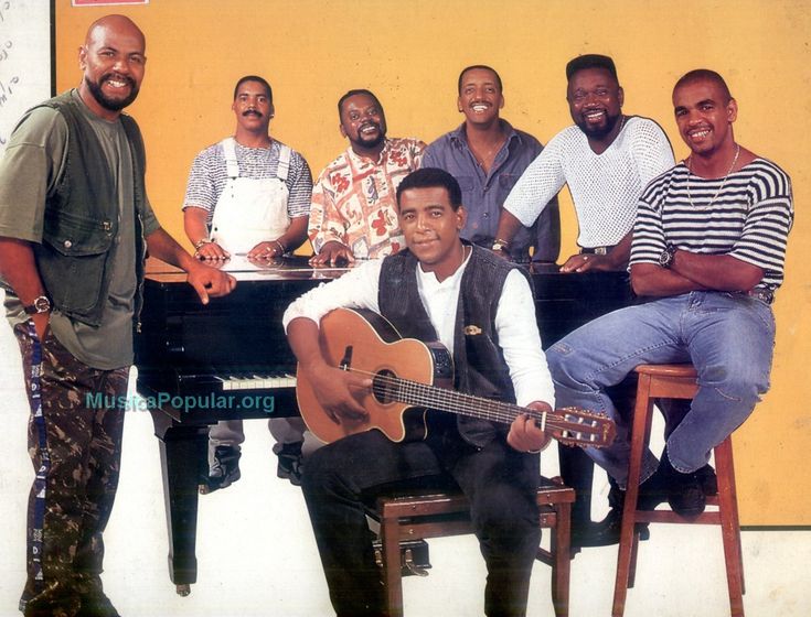 a group of men sitting around each other in front of a piano