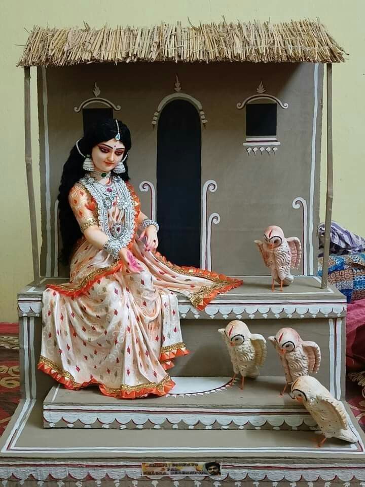 a statue of a woman sitting on top of a table next to two small birds