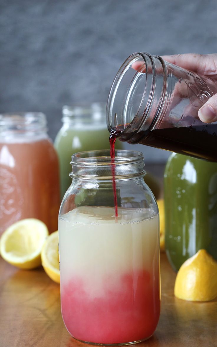 a person pouring liquid into a jar with lemons in the background